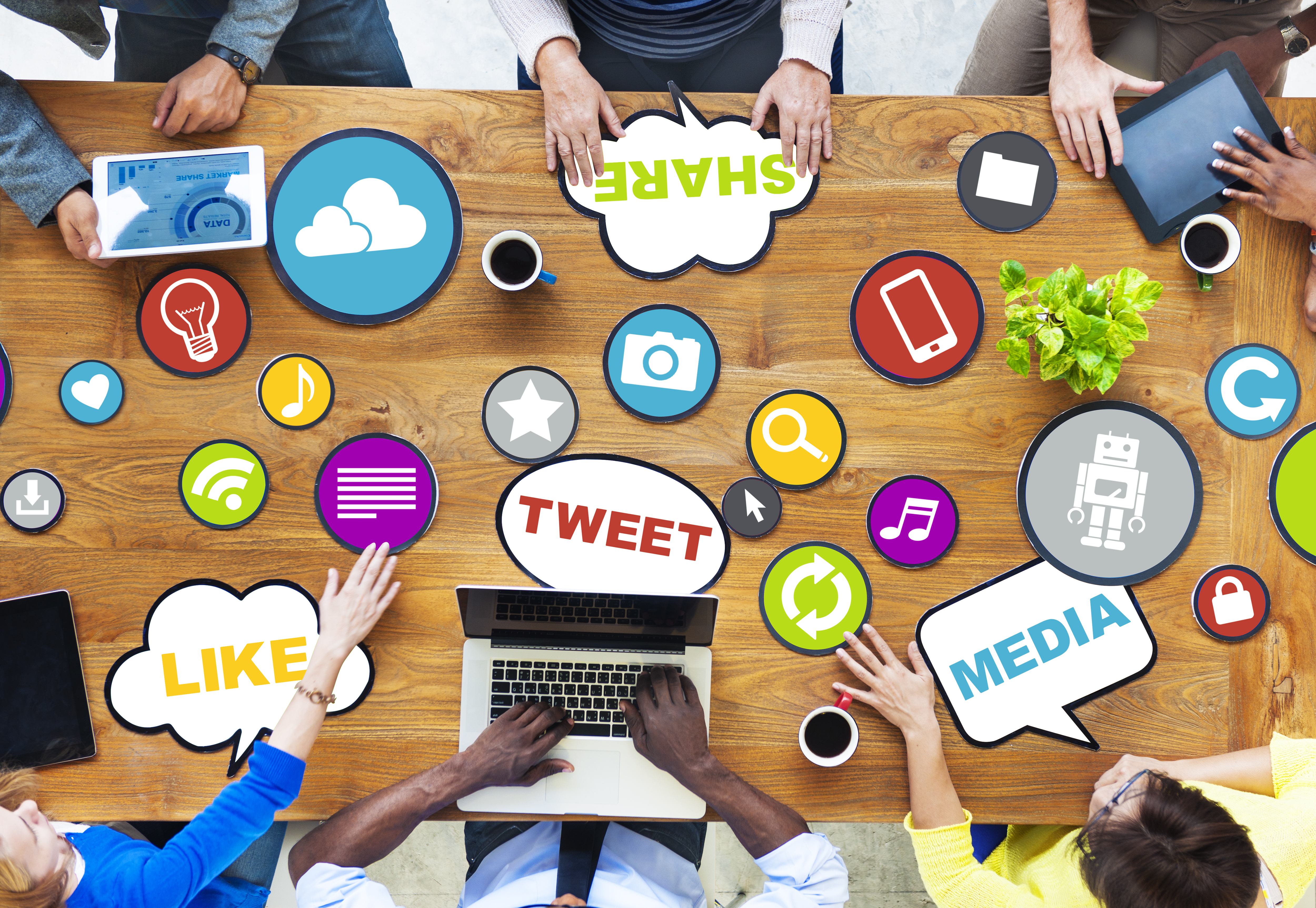 social media marketing; a generic image of a group of people discussing about social media - lots of social media related icons and images are displayed on the table like share, tweet, media, like...